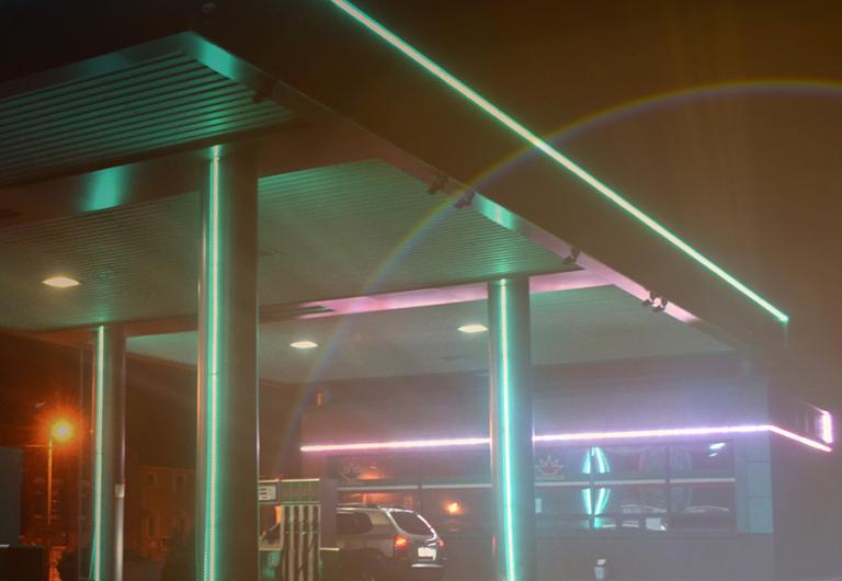 neon-lit gas station and convenience store with the sun rising, like a horizon